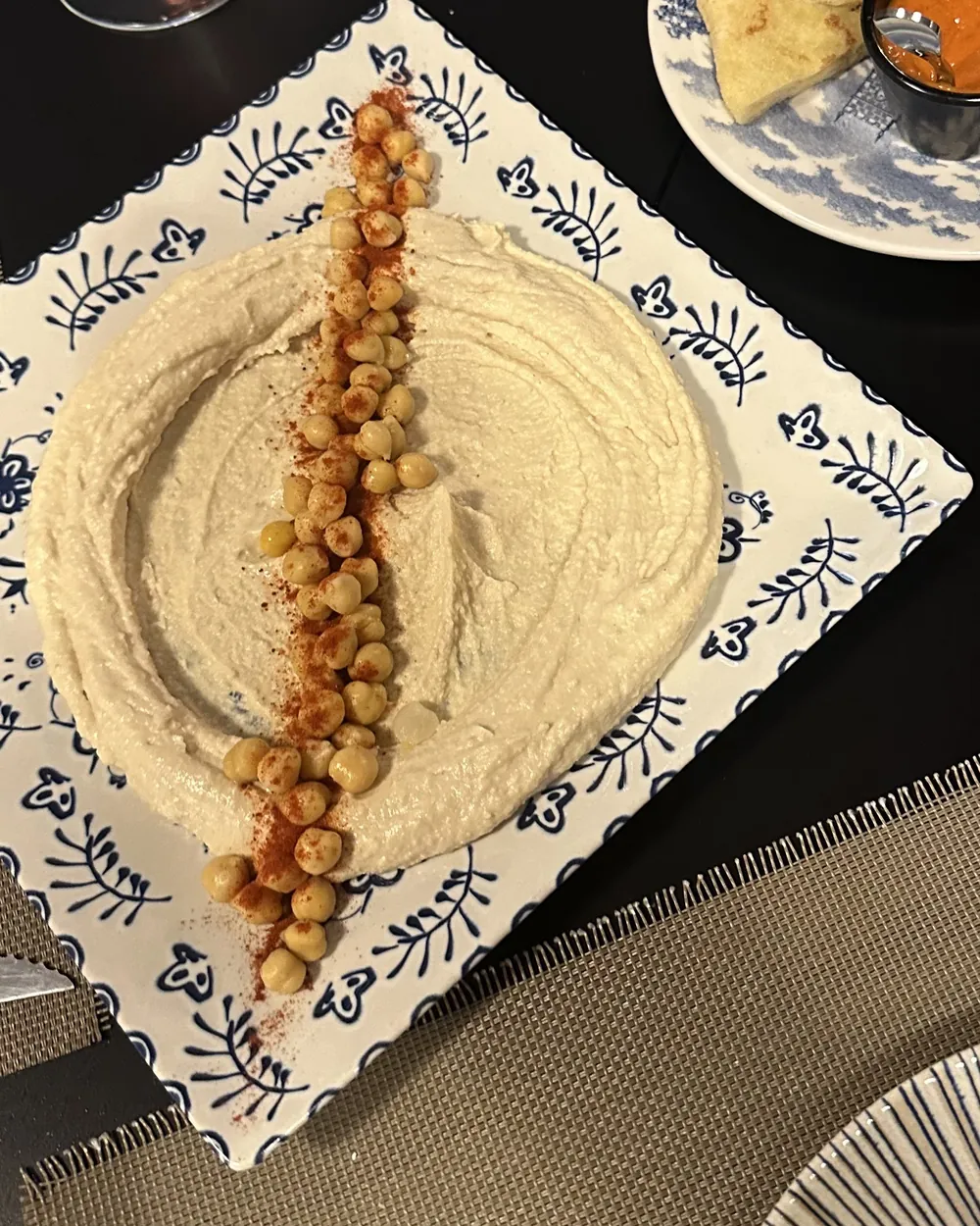 Hummus con garbanzos y pimentón en plato de Talavera, con pan khoubz y harissa